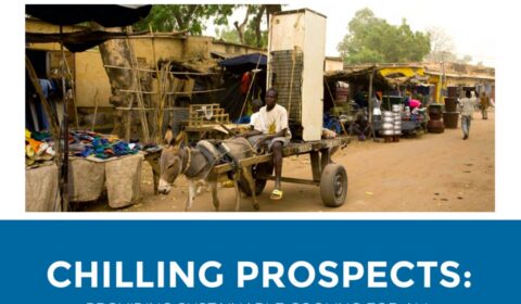 A man rides a donkey cart carrying a refrigerator through a market street with stalls and goods. Text below reads, CHILLING PROSPECTS: PROVIDING SUSTAINABLE COOLING FOR ALL..