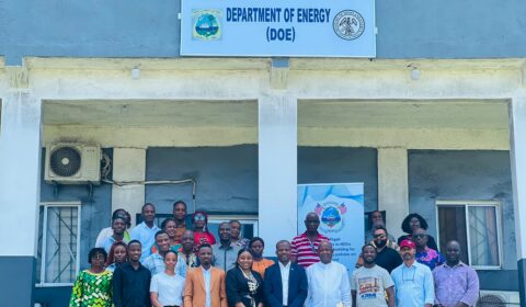 A group of people standing in front of the Department of Energy building for a formal photograph.